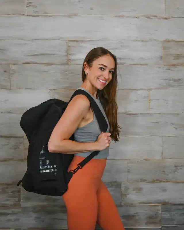 Woman wearing orange leggings and carrying a black tote bag.