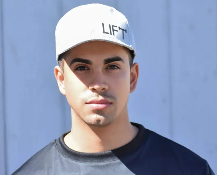 Man wearing a white cap with ’LIFT’ printed on it.