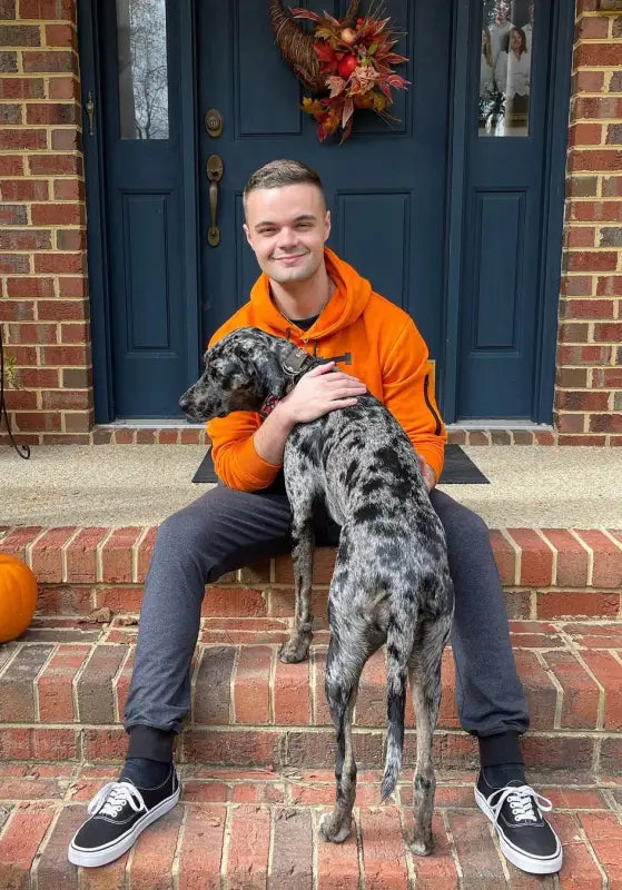 Person sitting on brick steps with a spotted dog.