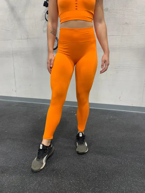 Bright orange workout outfit consisting of a crop top and high-waisted leggings.