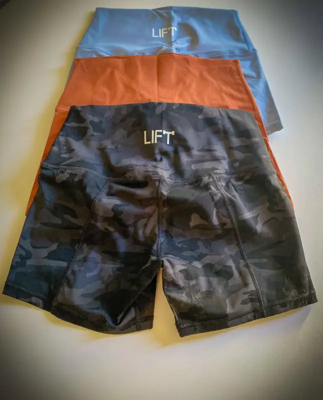 Athletic shorts in three different colors with ’LIFT’ printed on them.