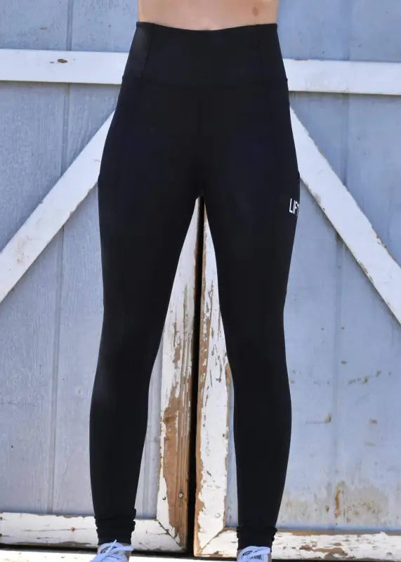 Black athletic leggings or tights worn on a person’s legs.