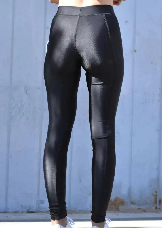Shiny black leather or faux leather leggings worn on a person’s lower body.