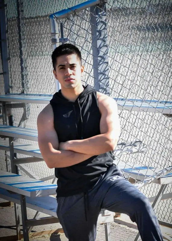 Young man with crossed arms sitting on bleachers.