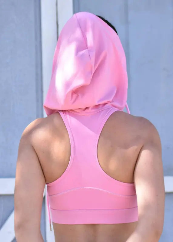 Pink sports bra or workout top with a hood pulled over the wearer’s head.