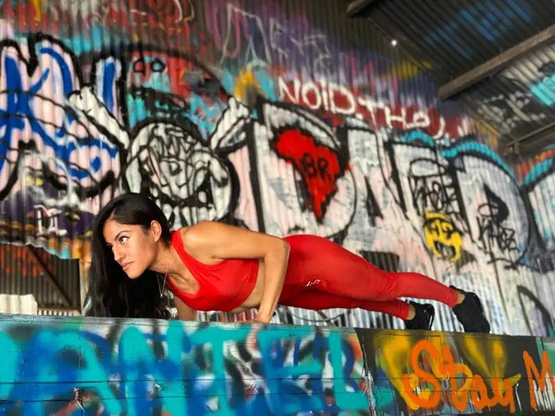 Woman in a red athletic outfit performing a plank exercise.