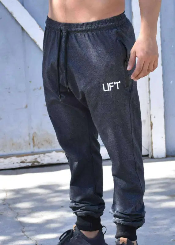 Black sweatpants with ’LIFT’ printed on the thigh.