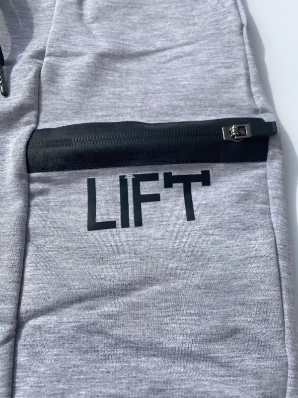 Gray sweatshirt with ’LIFT’ printed on it and a zippered pocket.